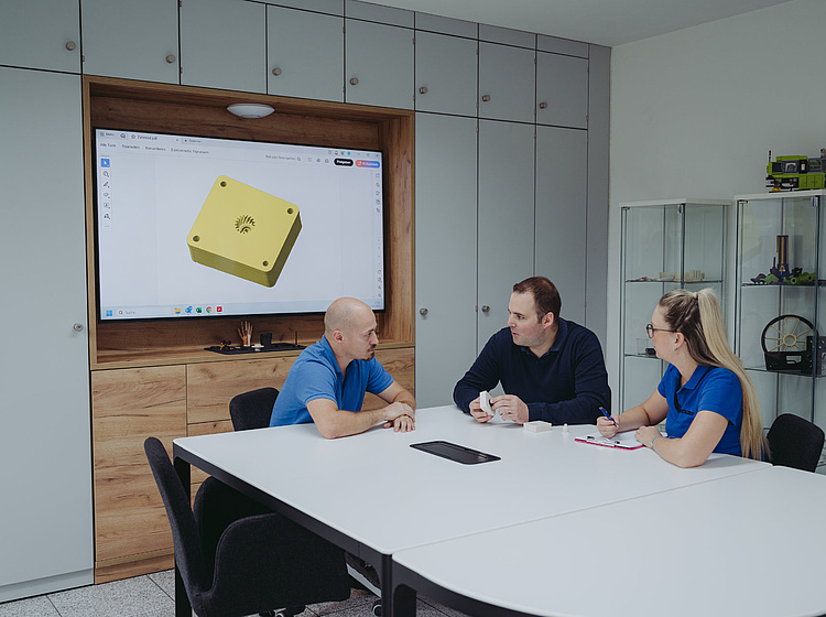3 Mitarbeiter sitzen an einem Tisch und planen ein Projekt 