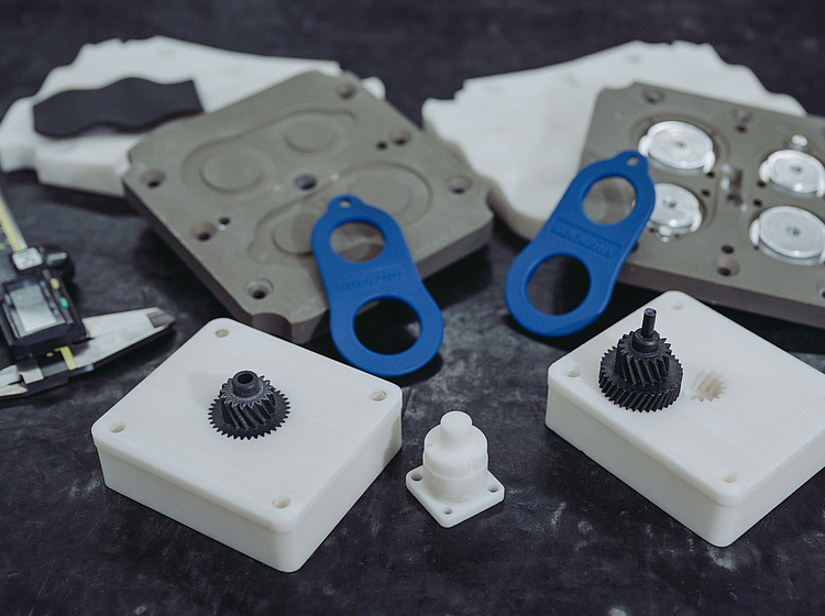 Bauteile und Werkzeuge im 3D-Druck liegen schön angeordnet auf einer Oberfläche