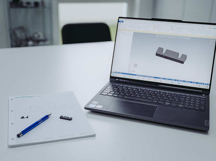 Laptop und Block mit Stift liegen auf einem Tisch für die Planung eines Bauteils 